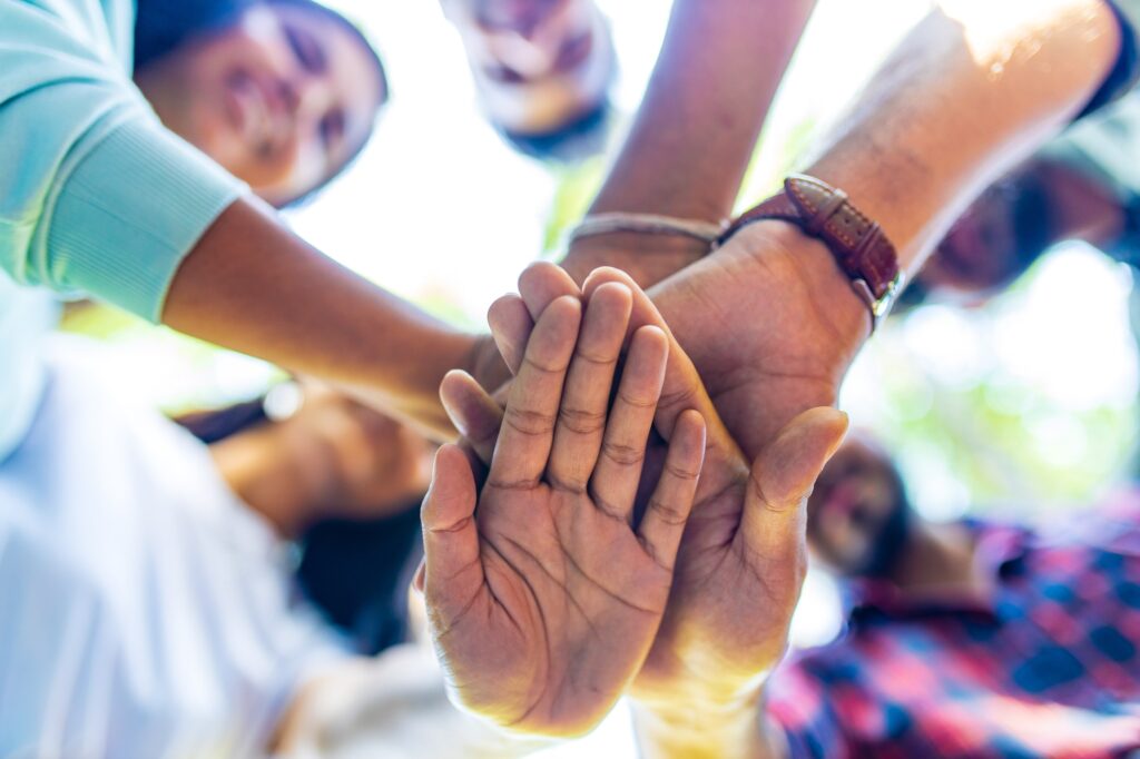 Diverse of big group of peoples hands together outdoors